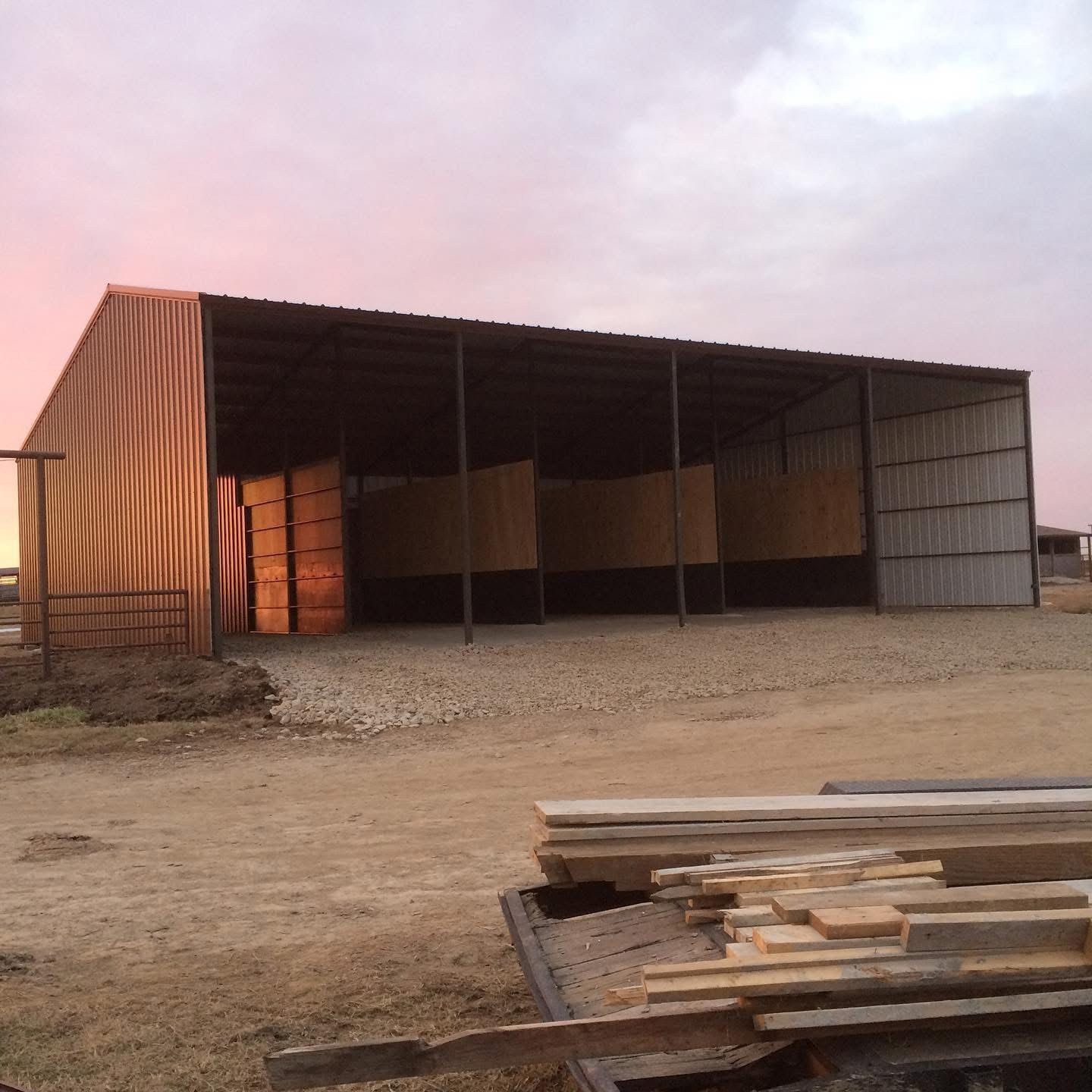 Finished open-front steel barn with stalls at sunrise